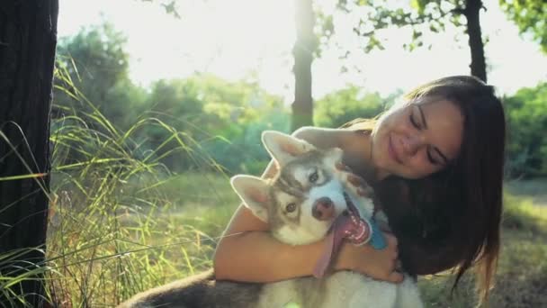 Tienermeisje strelen een husky hond in bos slow motion — Stockvideo