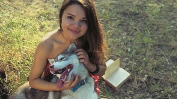 Teenage girl caresses a husky dog and looks in camera slow motion — Stock Video