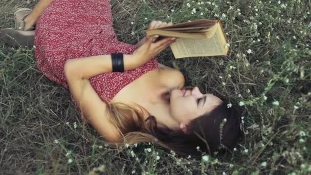 Jovem mulher coloca em flores de campo e lê um livro câmera lenta — Vídeo de Stock