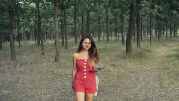Adolescente caminando en el bosque con una tableta de cámara lenta — Vídeos de Stock