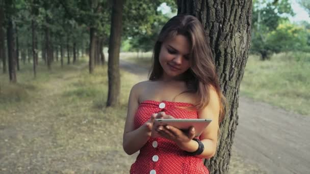Young woman uses a tablet pc in forest slow motion — Stock Video