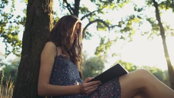 Jonge vrouw leest een boek in bos slow motion — Stockvideo