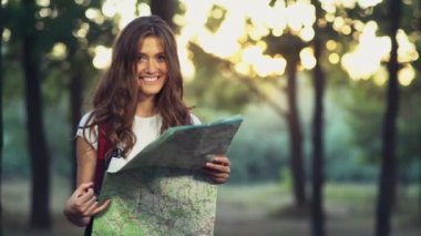 ormandaki bir harita ile genç erkek, kamera, gülümsüyor yavaş görünüyor