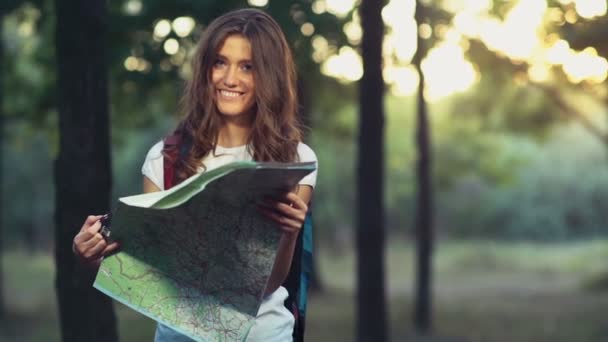 Fêmea sorridente com um mapa na floresta olha em câmera câmera câmera câmera lenta — Vídeo de Stock