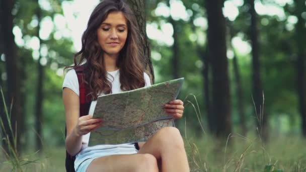 Femmina sorridente con una mappa nel bosco al rallentatore — Video Stock