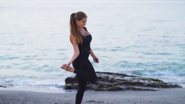 Молодая женщина практикует йогу на пляже замедленной съемки — стоковое видео
