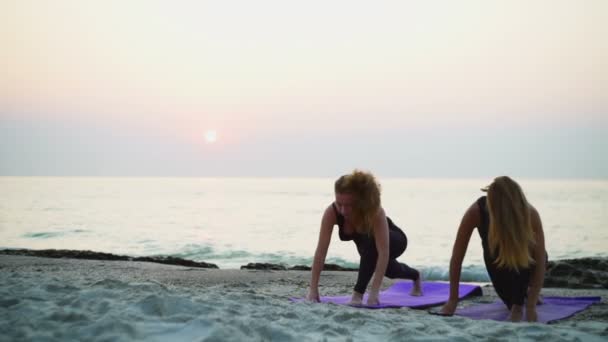 两个年轻女性练瑜伽上海滩慢动作 — 图库视频影像