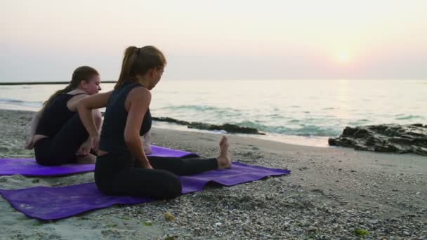 Iki genç kadın pratik yoga plaj yavaş hareket üzerinde — Stok video