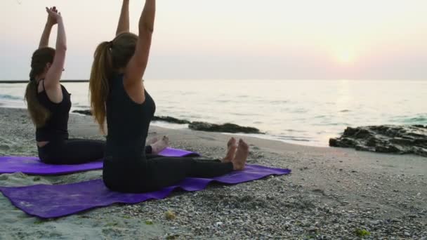 Iki genç kadın pratik yoga plaj yavaş hareket üzerinde — Stok video