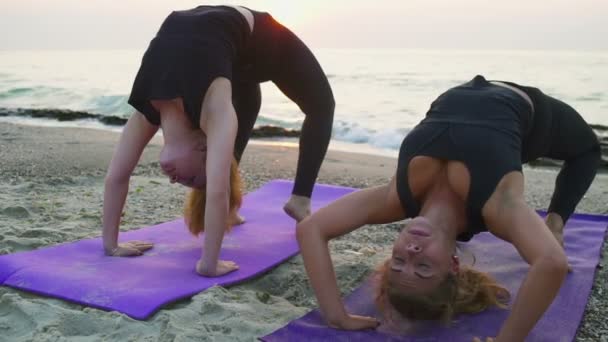 Twee jonge vrouwen praktijk yoga op het strand slow motion — Stockvideo