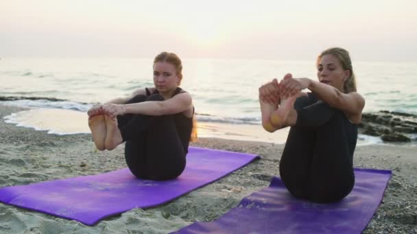 Iki genç kadın pratik yoga plaj yavaş hareket üzerinde — Stok video