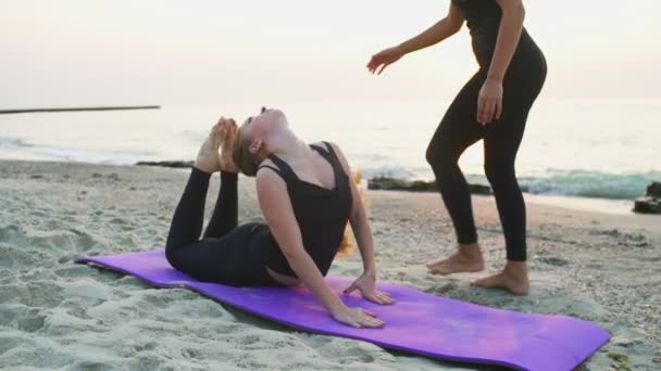 Две молодые женщины практикуют йогу на пляже замедленной съемки — стоковое видео