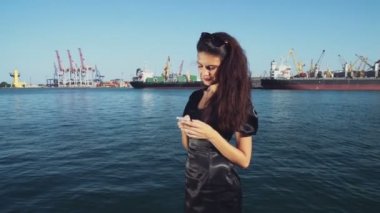 şık iş kadını bir smartphone seaport ağır çekimde kullanır.