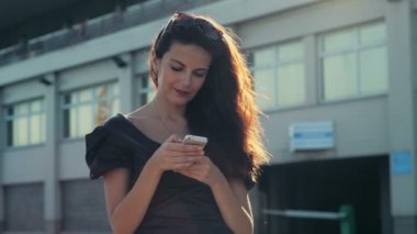 zarif Bayan bir smartphone ve gülümsüyor sokak ağır çekimde kullanır