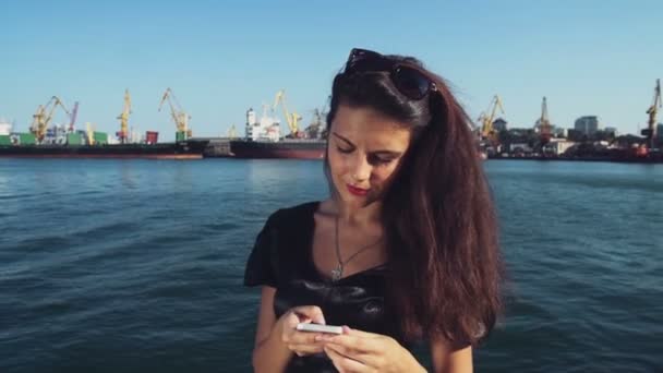 Elegante dama de negocios envía un mensaje por teléfono en el puerto — Vídeo de stock