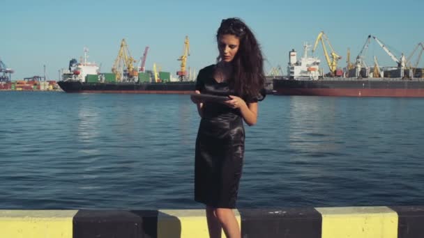 Elegante mujer de negocios utiliza una tableta en el puerto de cámara lenta — Vídeos de Stock