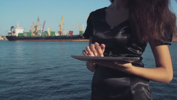 Elegant business woman uses a tablet computer in the seaport slow motion — Stock Video