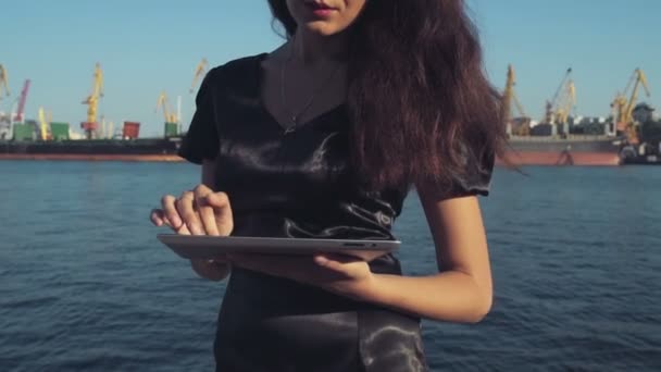 Elegant business woman uses a tablet computer in the seaport slow motion — Stock Video