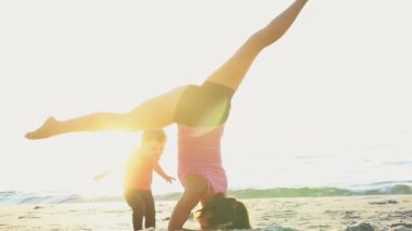 annenin çocuğunu üzerinde plaj yavaş hareket ile jimnastik yaptığı