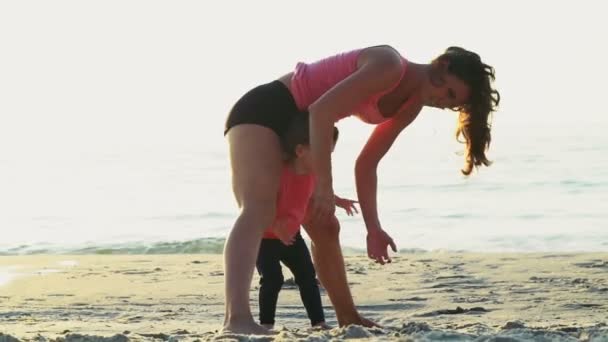 Moeder doet gymnastiek met haar kind op het strand slow motion — Stockvideo