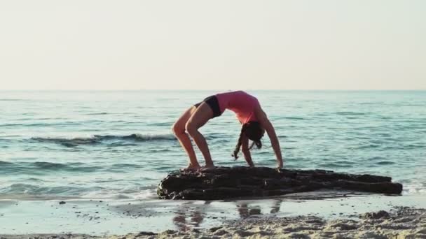 Jonge vrouw doet gymnastiek op het strand slow motion — Stockvideo