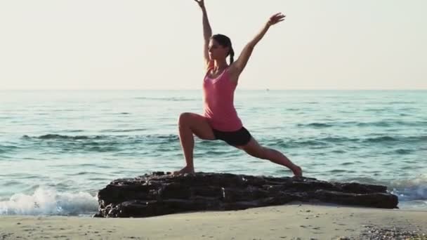 Jonge vrouw doet gymnastiek op het strand slow motion — Stockvideo