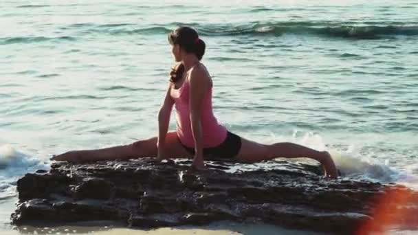 Jonge vrouw doet gymnastiek op het strand slow motion — Stockvideo