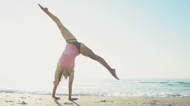 Jovem do sexo feminino faz ginástica na praia câmera lenta — Vídeo de Stock