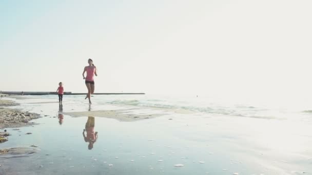 Mutter und Kind rennen in Zeitlupe am Strand entlang — Stockvideo