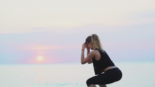 Ung kvinna gör knäböj på stranden slow motion — Stockvideo