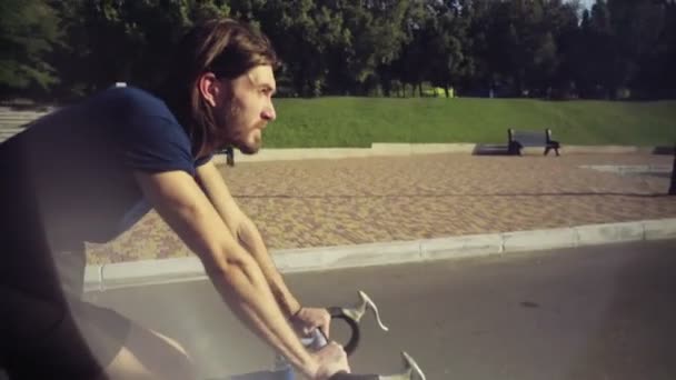 Ung vacker man rider en cykel i parken slow motion — Stockvideo