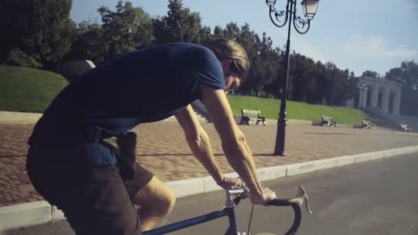 Jonge knappe man rijdt een fiets in de park slow motion — Stockvideo