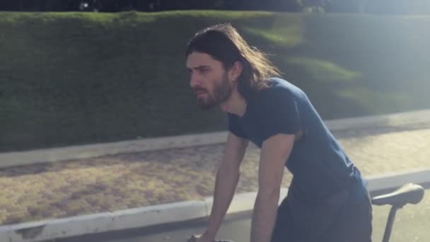 Joven guapo hombre monta una bicicleta en el parque cámara lenta — Vídeo de stock