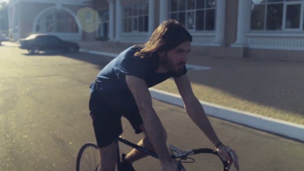 Ung vacker man rider en cykel i gatan slow motion — Stockvideo