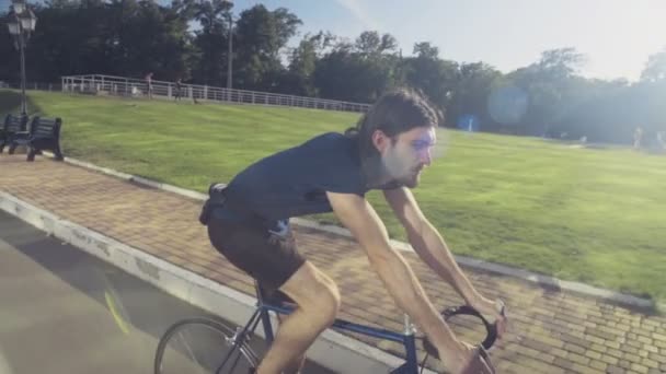 年轻英俊的男子骑着自行车穿越公园慢动作 — 图库视频影像