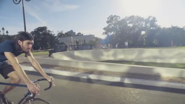 Jonge knappe man rijdt een fiets door het park slow motion — Stockvideo