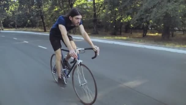 Joven guapo hombre montar una bicicleta en el parque cámara lenta — Vídeo de stock