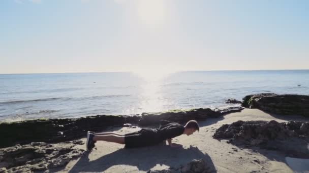 Corridore maschio riscaldamento un la luce del sole sulla spiaggia rallentatore — Video Stock