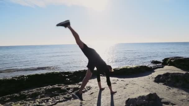 Jonge man doen gymnastiek op het strand slow motion — Stockvideo