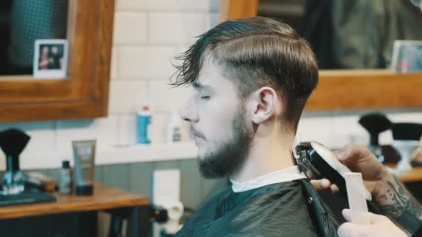 Kapper snijdt de haren van de client met clipper — Stockvideo