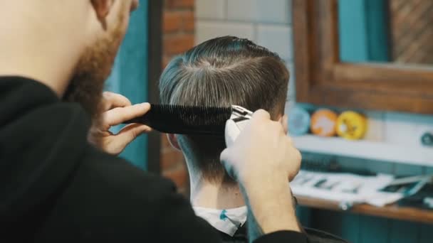 Barber coupe les cheveux du client avec une tondeuse — Video