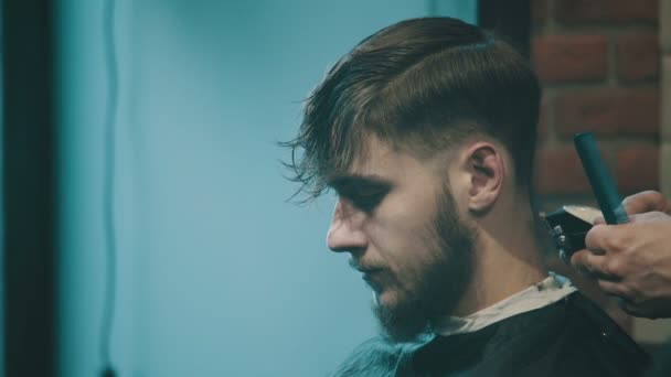 Парикмахер стрижет волосы клиента клиппером — стоковое видео