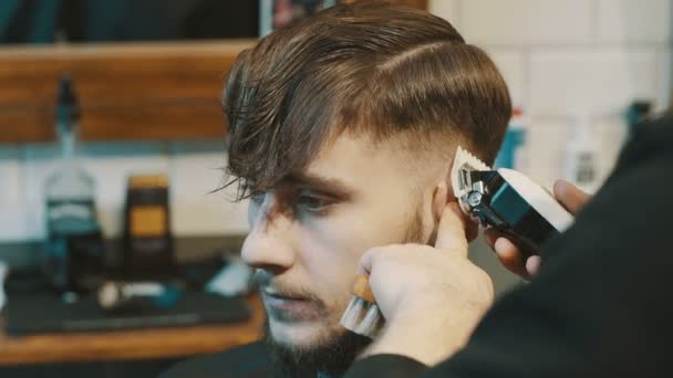 Peluquero corta el cabello del cliente con un cortador — Vídeos de Stock