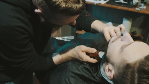 Barber oholit vousy klienta s trávníků — Stock video