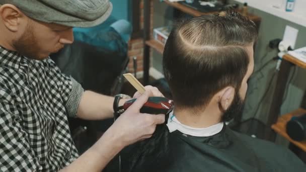 Парикмахер стрижет волосы клиента триммером — стоковое видео
