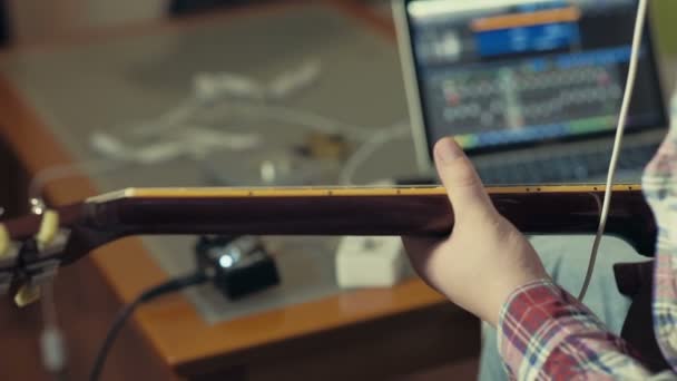 Uomo suonare la chitarra elettrica con il computer portatile in background slow motion — Video Stock