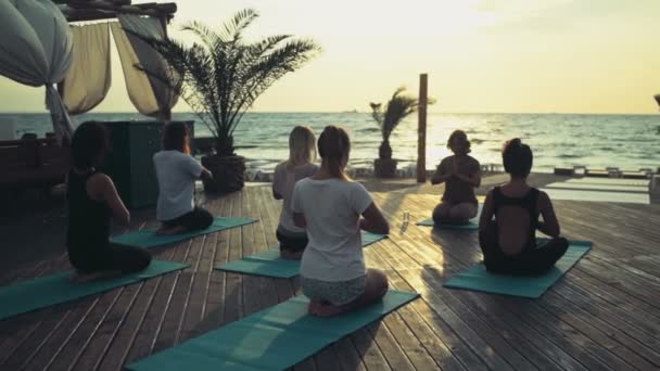 Grupp kvinnor som utövar yoga på stranden slow motion — Stockvideo