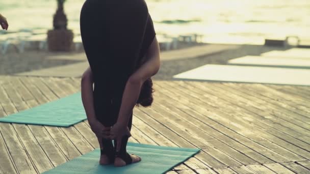 Молодая женщина практикует йогу на пляже утром — стоковое видео