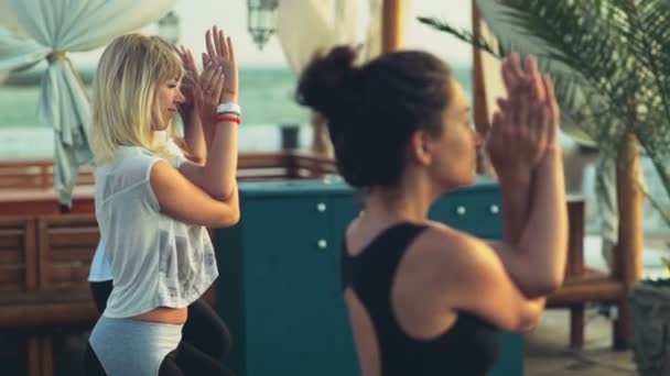 Grupp kvinnor som utövar yoga på stranden slow motion — Stockvideo