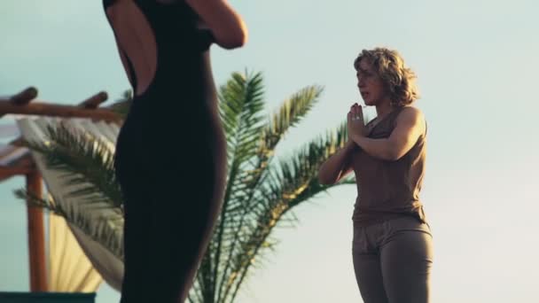 Две женщины, посредничающие на пляже — стоковое видео